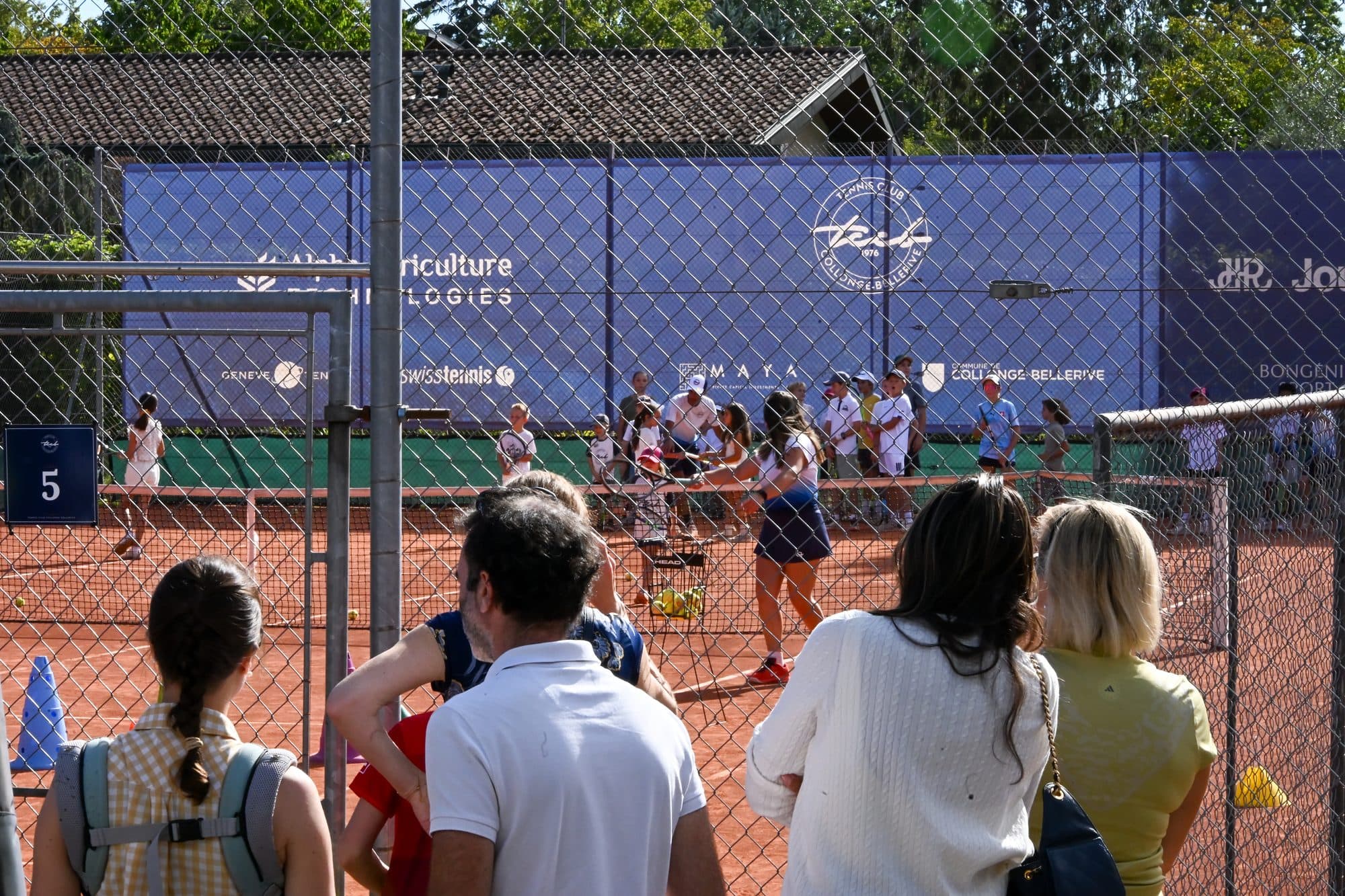Parents et enfants au bord des courts en terre battue pendant les animations