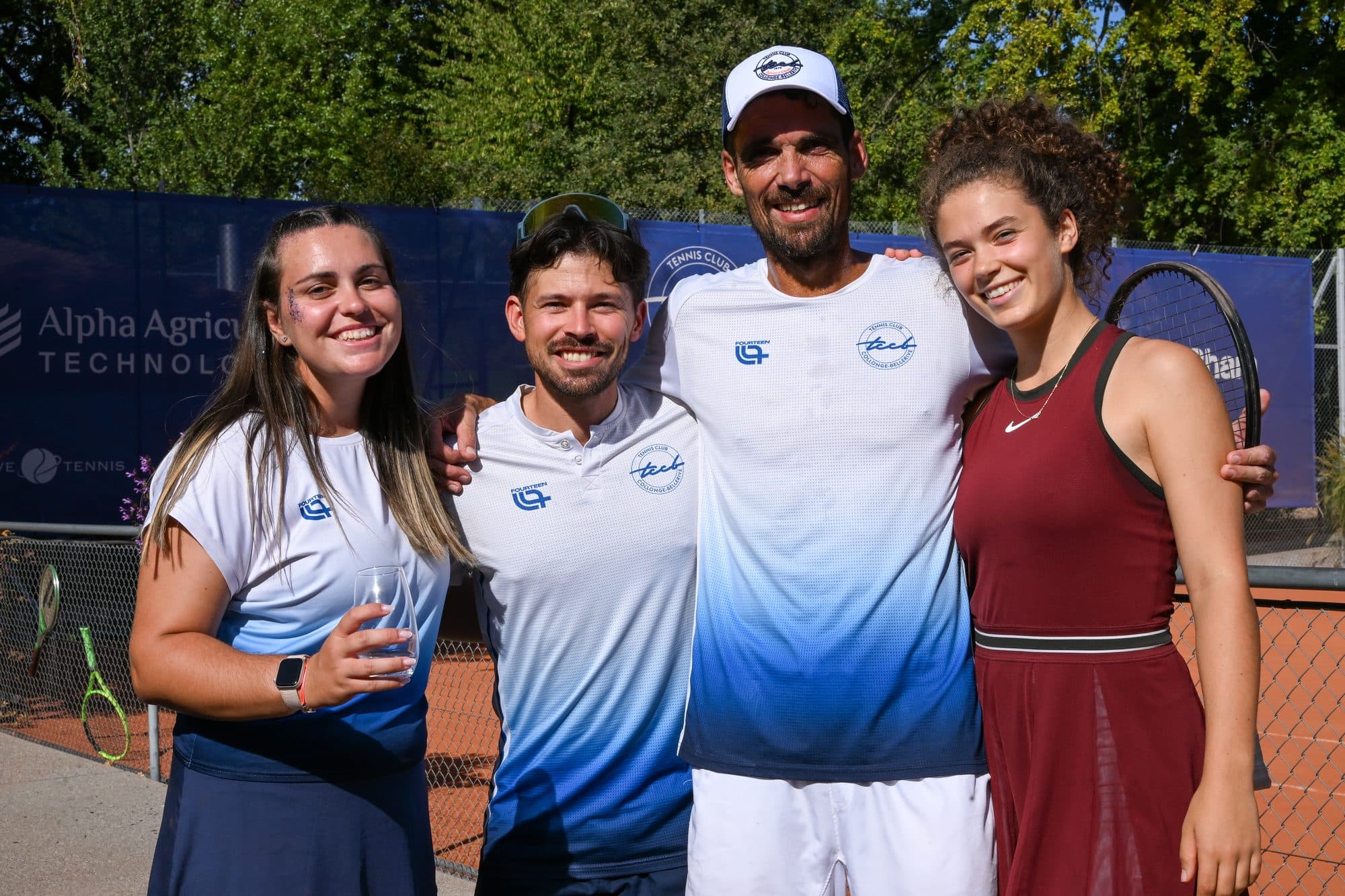 Deux coachs et deux joueuses réunis, sourire aux lèvres, au bord du court